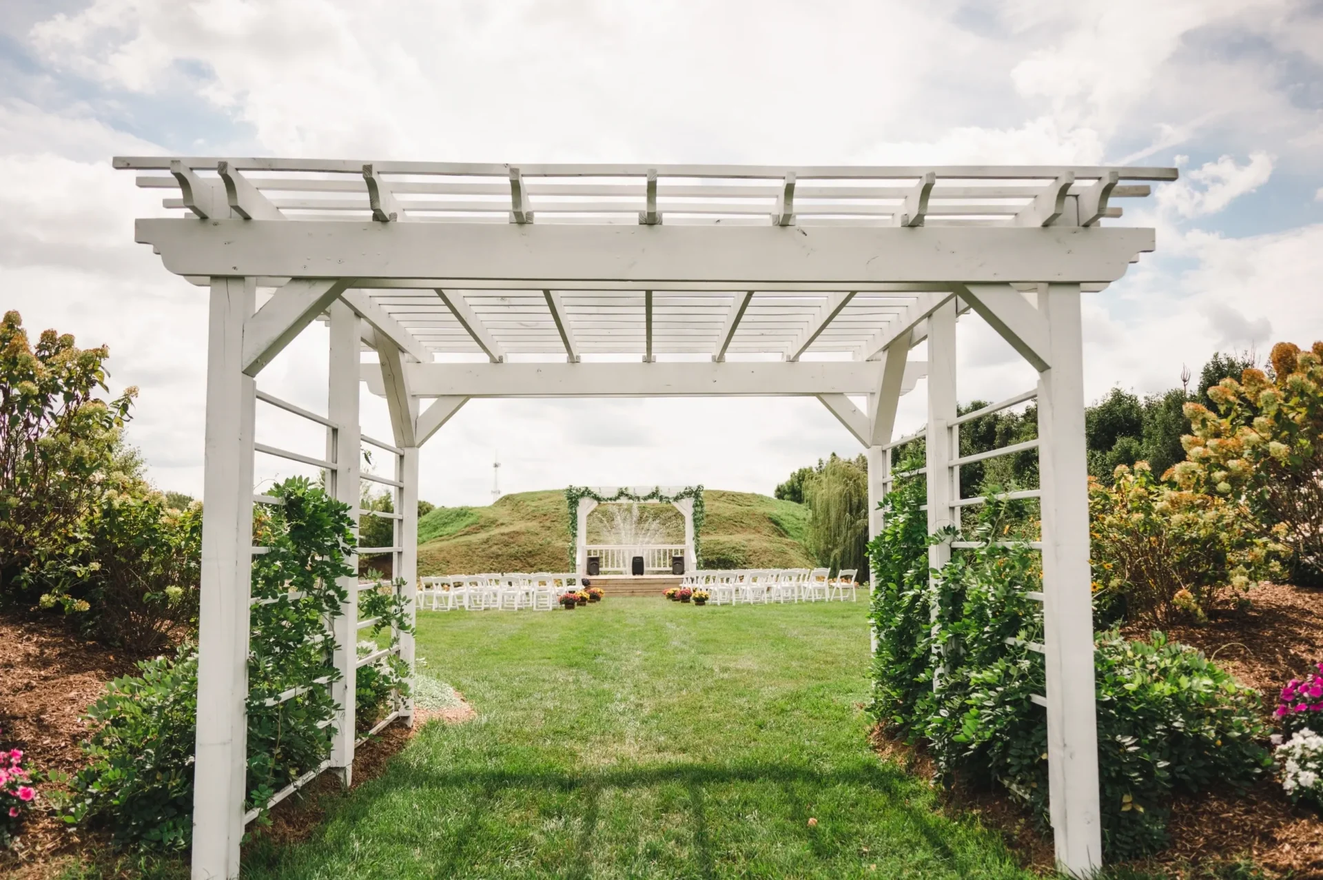 White pergola framing outdoor wedding aisle and arch