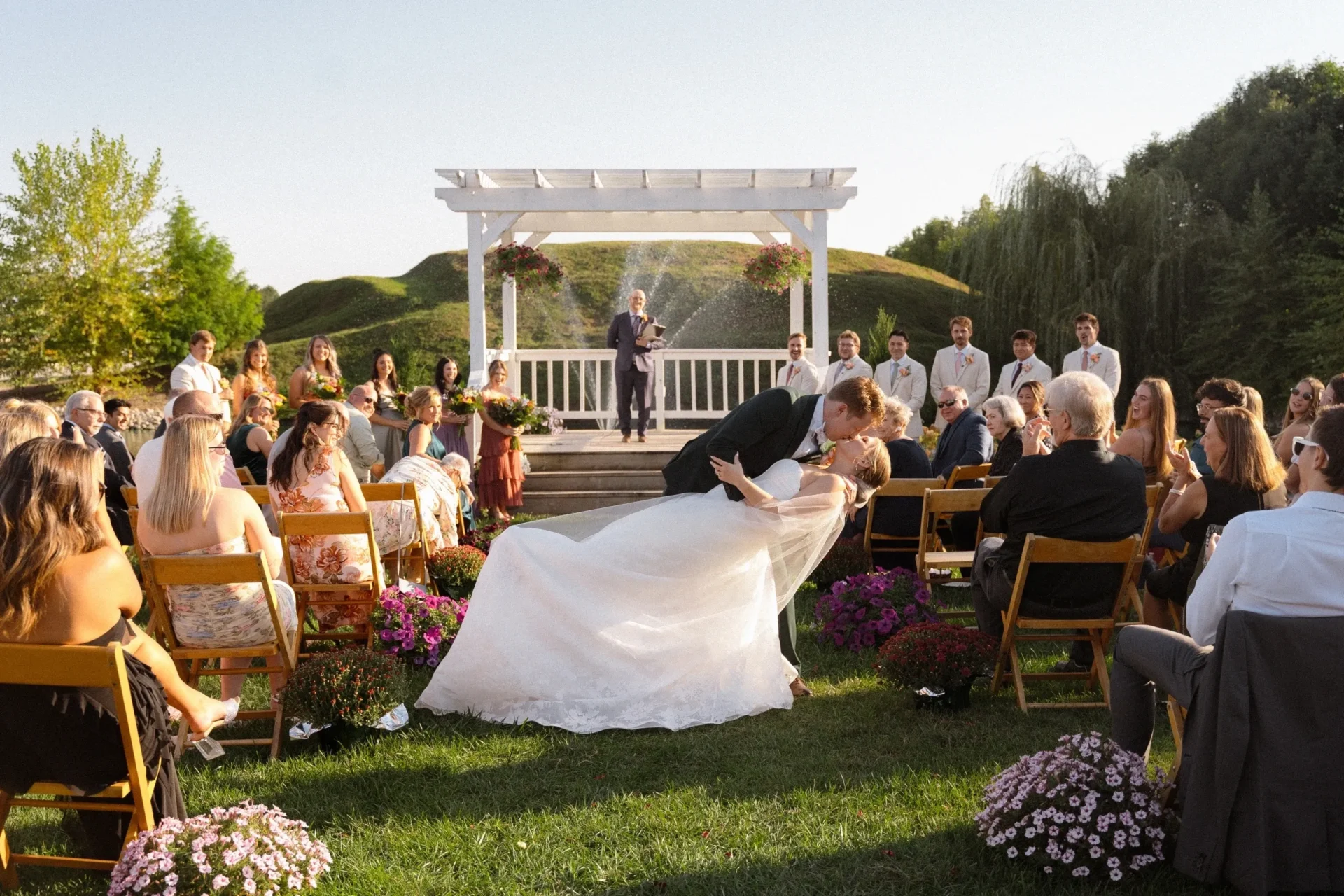 Outdoor ceremony kiss with cheering guests