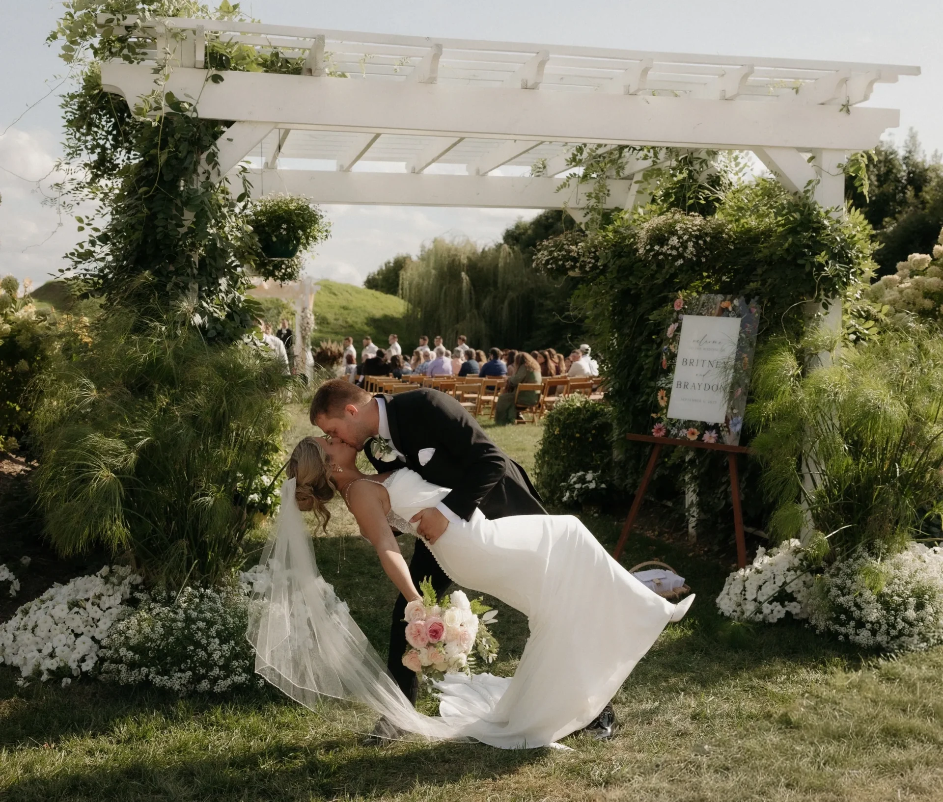 Groom dipping bride under floral arch