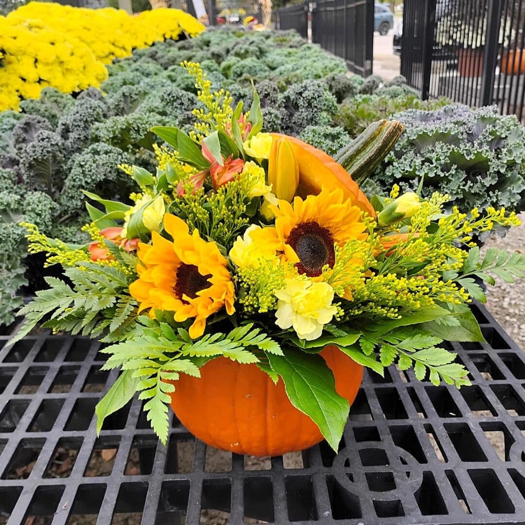 Fresh pumpkin filled with sunflowers, yellow flowers, and greenery, showing an example of the centerpiece participants will create.